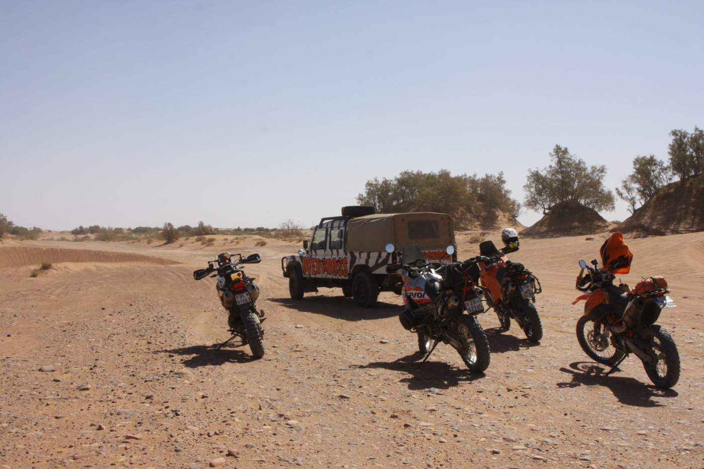 Motorräder und das Versorgungsfahrzeug Landrover Defender in den Sanddünen vor der Oasenstadt Mhamid 