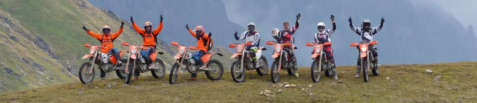 Gruppe auf dem Grat, Arme in der Luft, Enduros am Pass