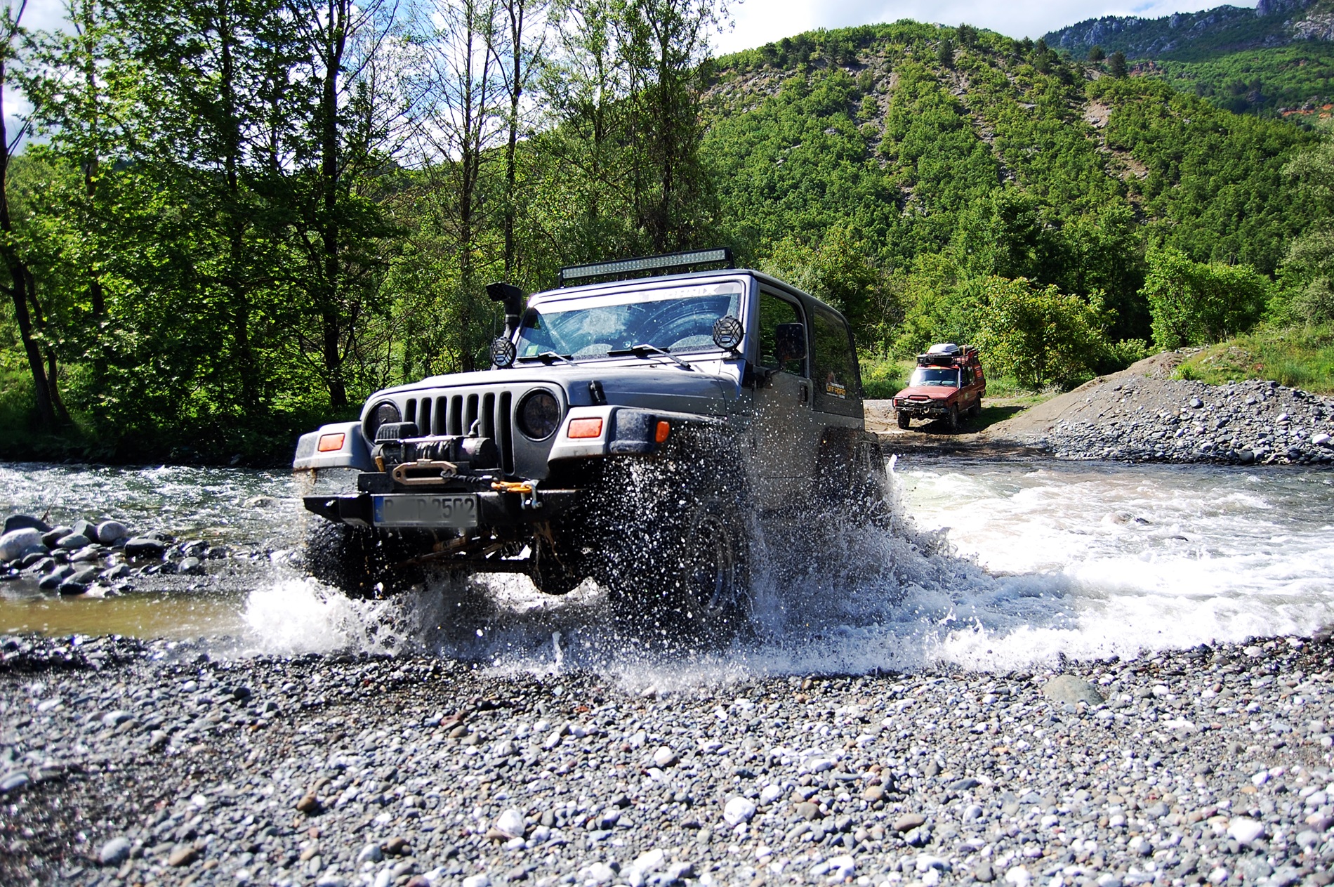 Geländewagen bei einer Flussdurchfahrt in den Bergen Albaniens
