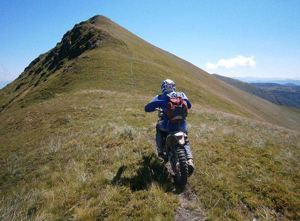 Enduro-Fahrer erklimmt einen schmalen Bergkamm in den ukrainischen Karpaten.