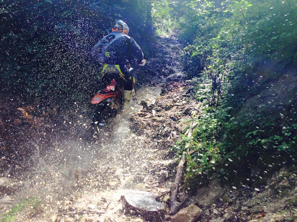 Enduro-Fahrer durchquert spritziges, schlammiges Waldgelände.