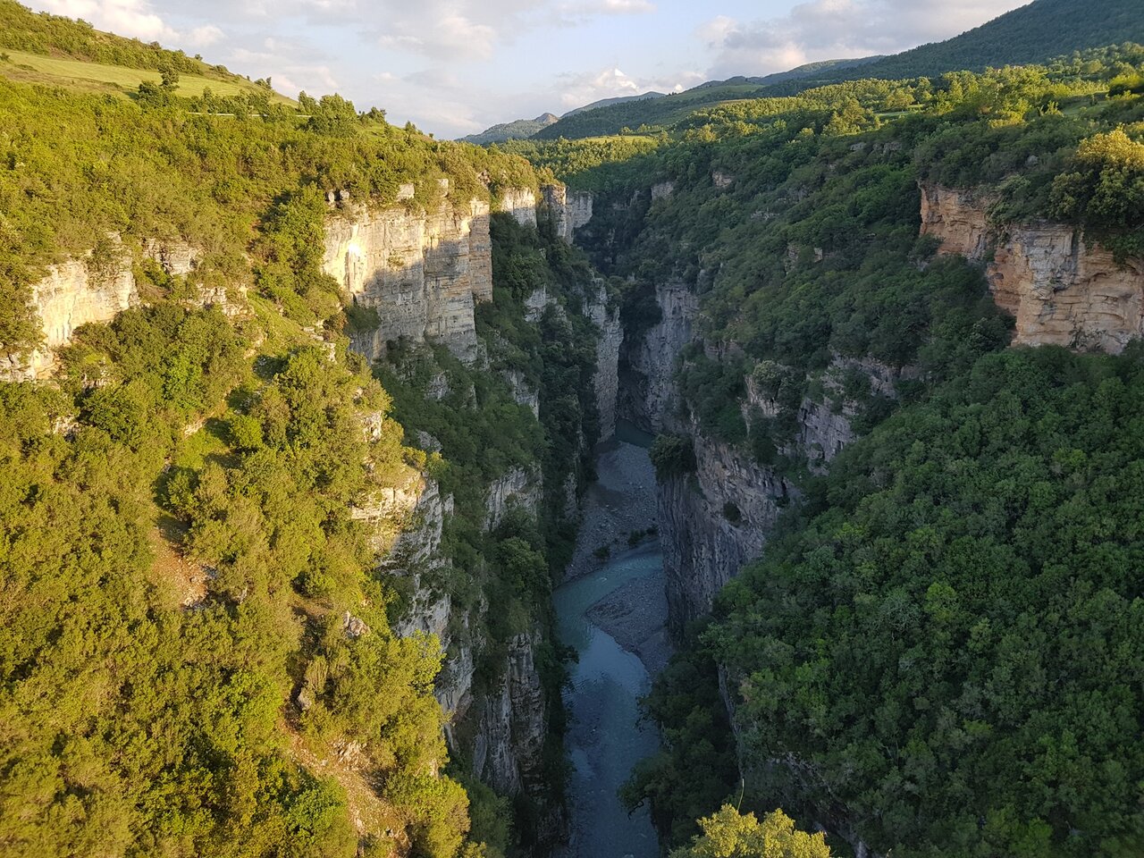 Tiefe Kalksteinschlucht mit einem Fluss, der sich zwischen bewaldeten Klippen schlängelt