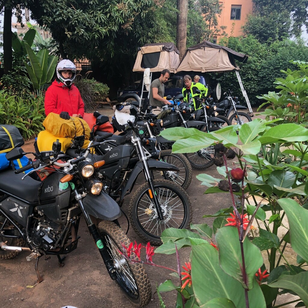 Geparkte Motorräder und ein Begleitfahrzeug mit Dachzelten in einem Gartencamp