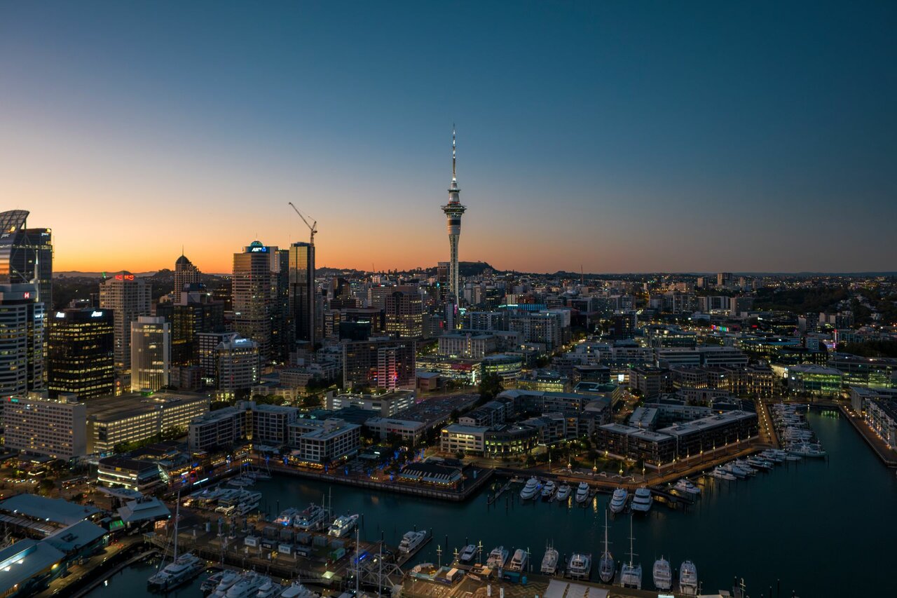 Auckland-Skyline in der Dämmerung mit dem Sky Tower und einem Jachthafen voller Boote