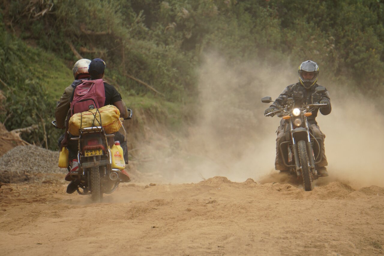 Um motociclista atravessa uma nuvem de poeira atrás de outro piloto numa pista de terra