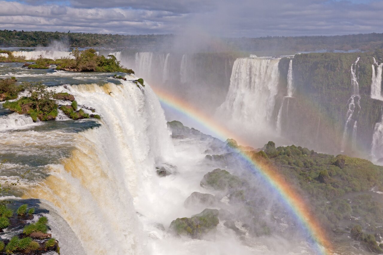 Die Iguazu Falls stürzen über Klippen, ein Regenbogen im aufsteigenden Nebel