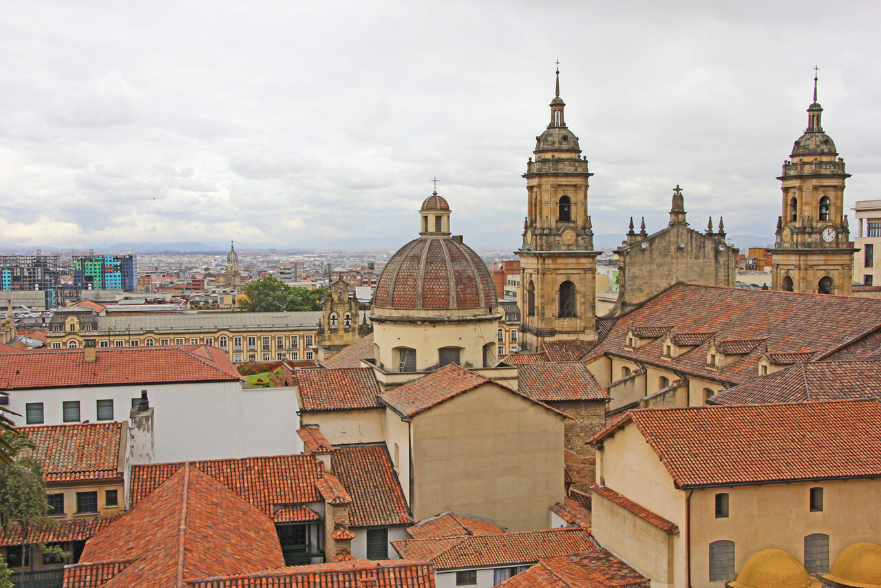 Vista do alto sobre um centro histórico, com telhados de terracota, cúpulas de igrejas e torres sineiras