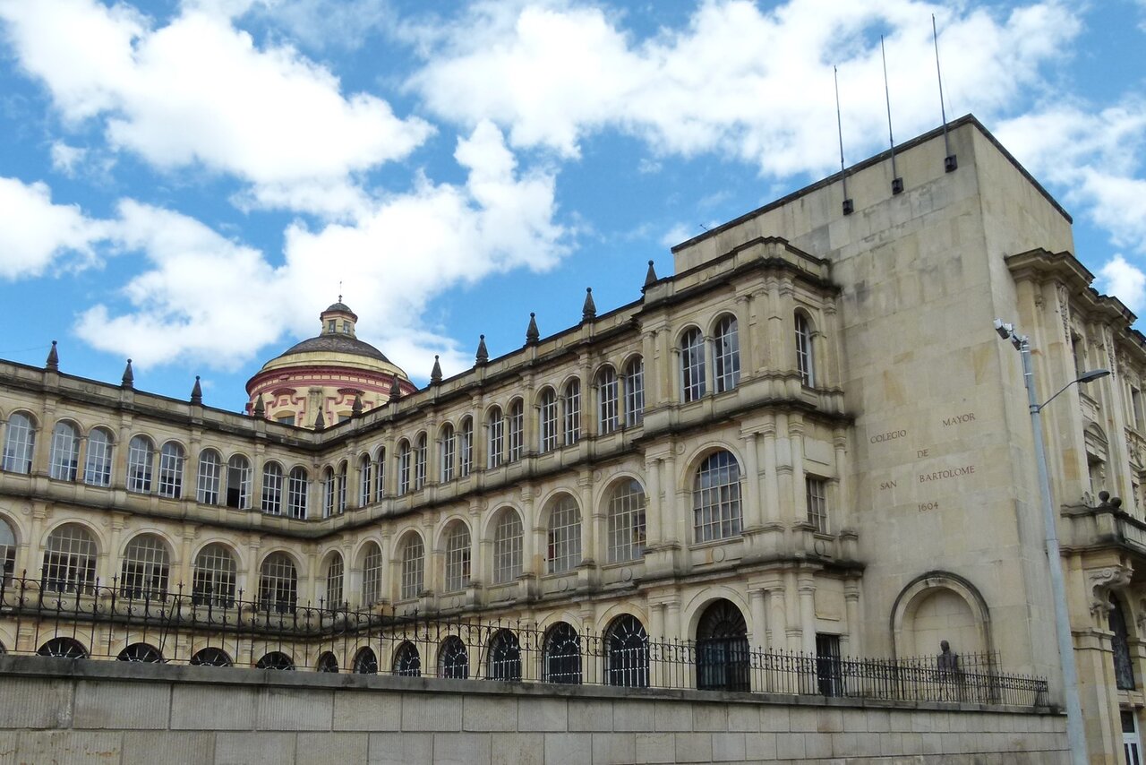 Fachada em pedra do Colegio Mayor de San Bartolome, com a data de 1604 gravada, sob um céu azul