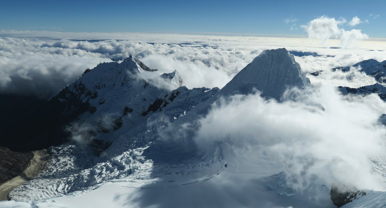 Wolkenumhüllte Schneegipfel der Cordillera Blanca im Wechsel von Sonne und Schatten