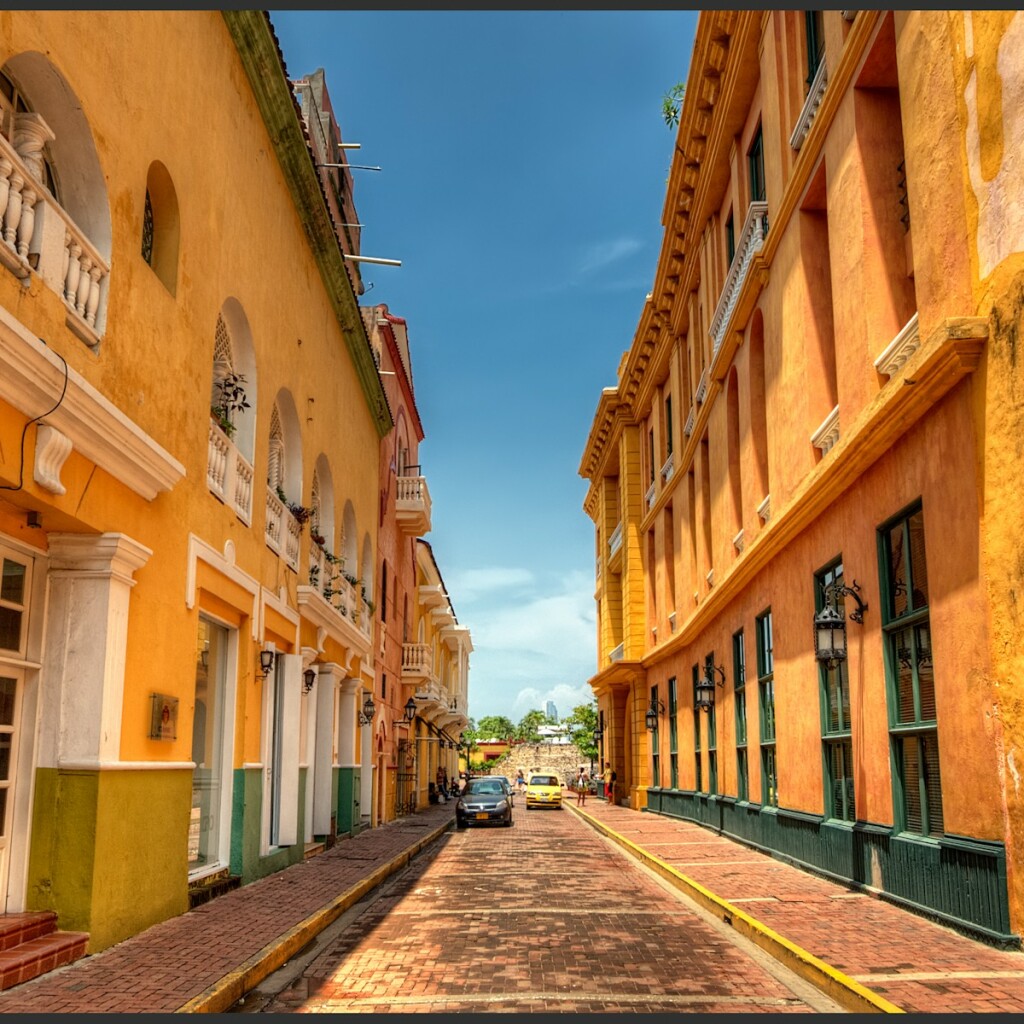 A narrow colonial street lined with orange buildings under a bright blue sky