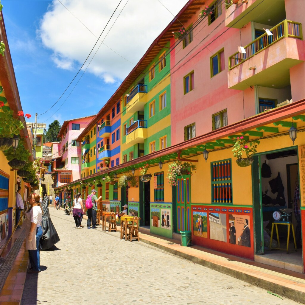A cobblestone street lined with brightly painted buildings and mural panels