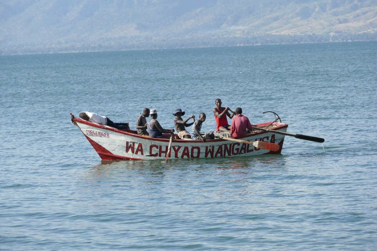 Ein bemaltes Holzfischerboot mit mehreren Männern auf einem großen See