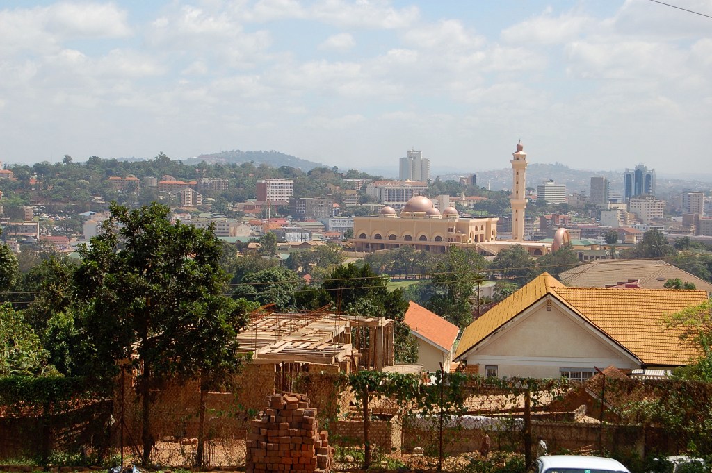 Luftaufnahme von Kampala mit einer Kuppelmoschee und einem Minarett zwischen Dächern und Hügeln