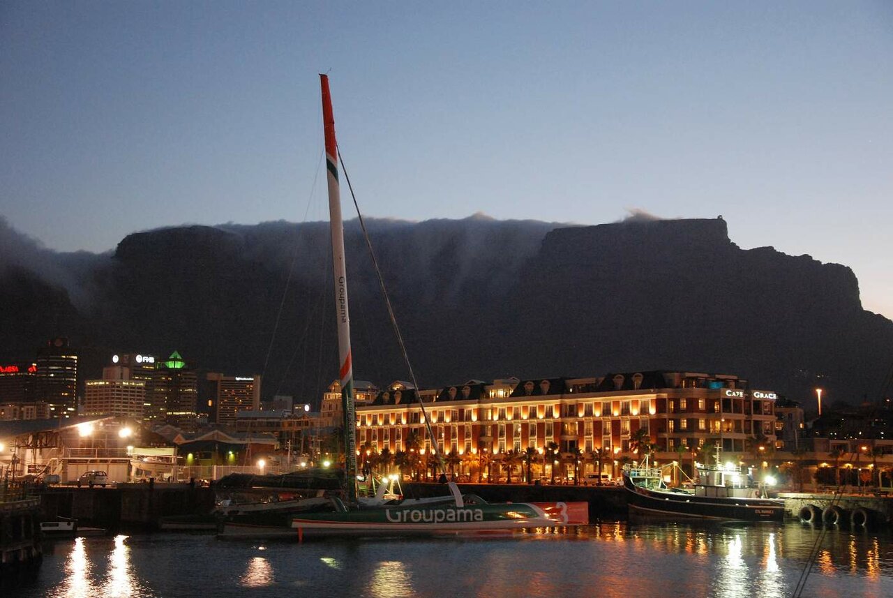Cape Town waterfront at dusk with a racing yacht at the dock and Table Mountain silhouetted behind