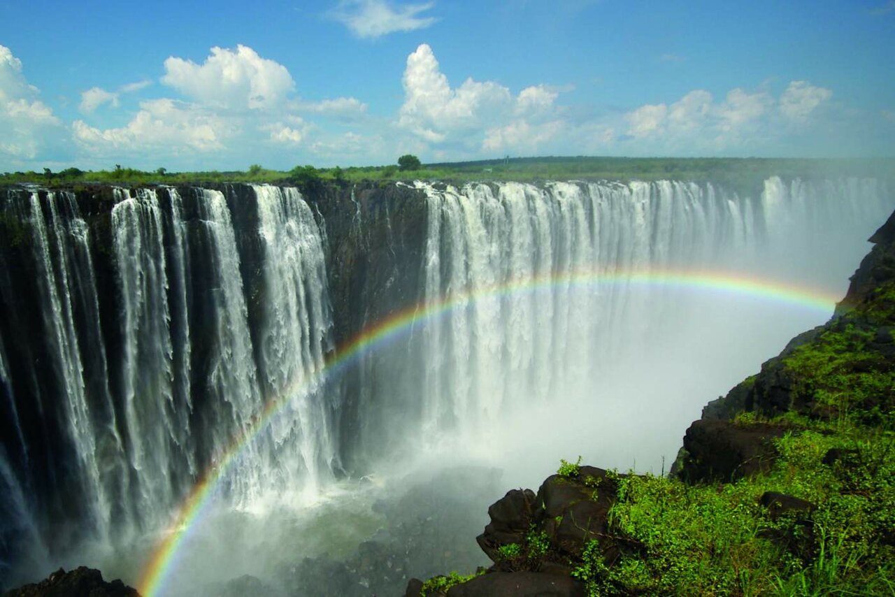 Victoria Falls with a rainbow rising from the spray over the gorge