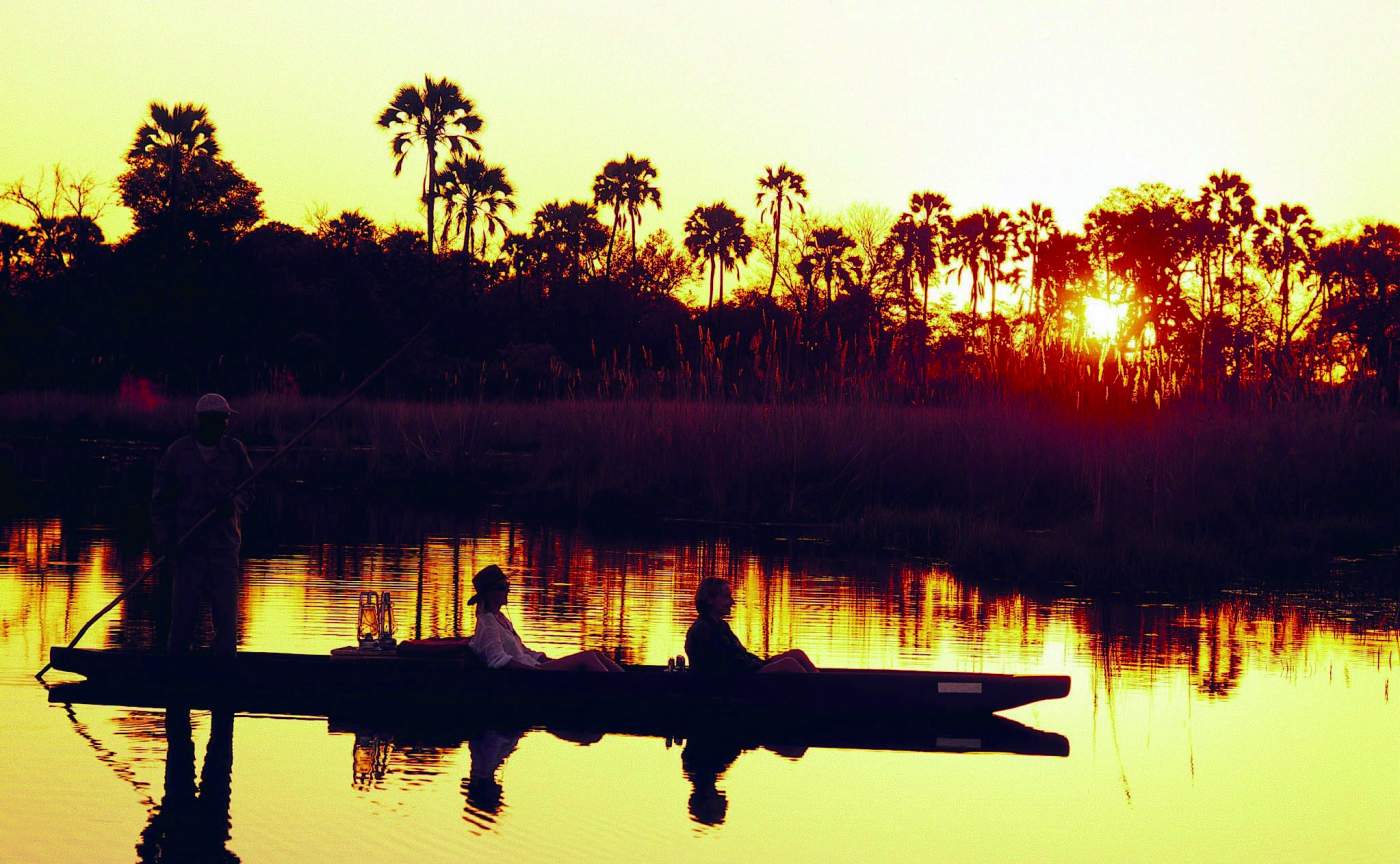 Kanufahrt bei Sonnenuntergang im Okavango Delta