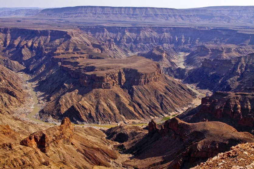 Luftaufnahme des Fish River Canyon mit geschichteten Felswänden und dem gewundenen Fluss darunter