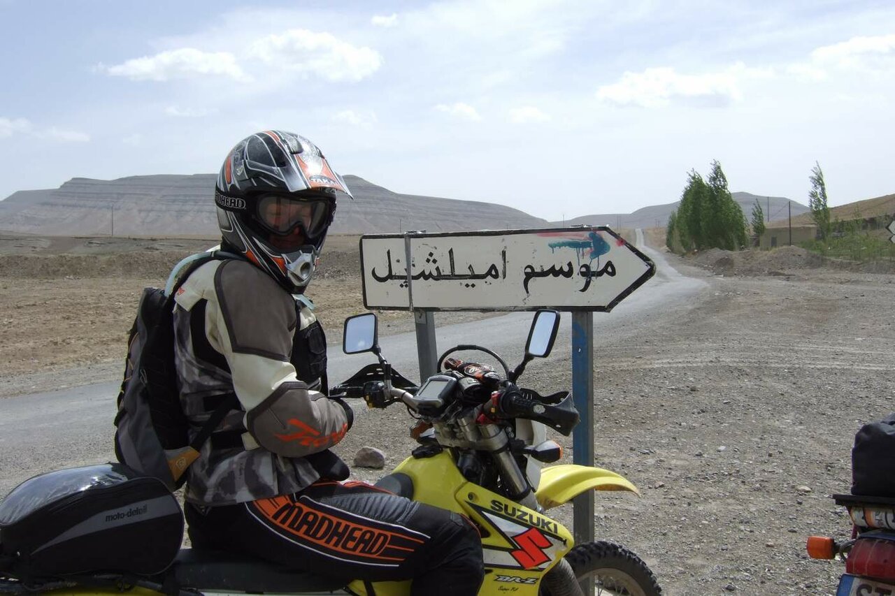 A motorcyclist kicks up a huge cloud of orange dust while riding through the dunes