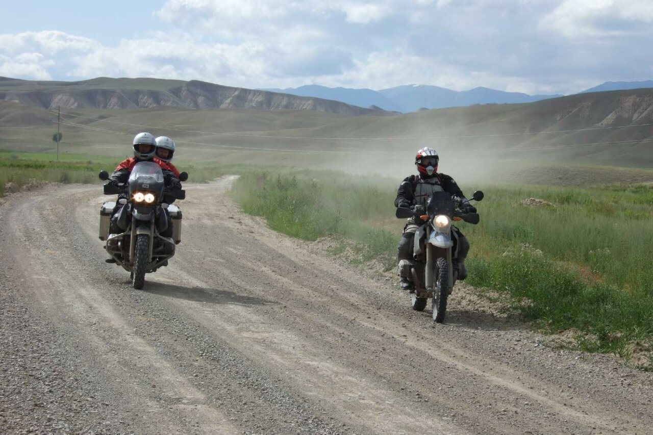 Cinco personas descansan en una mesa de picnic junto a la carretera con cuatro motos aparcadas detrás