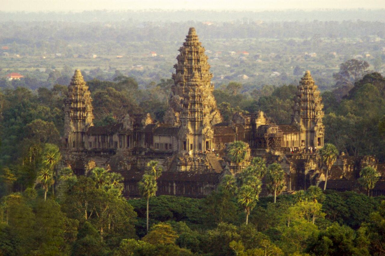 La torre central de Angkor Wat se eleva sobre el dosel de la selva, vista a lo lejos con luz brumosa