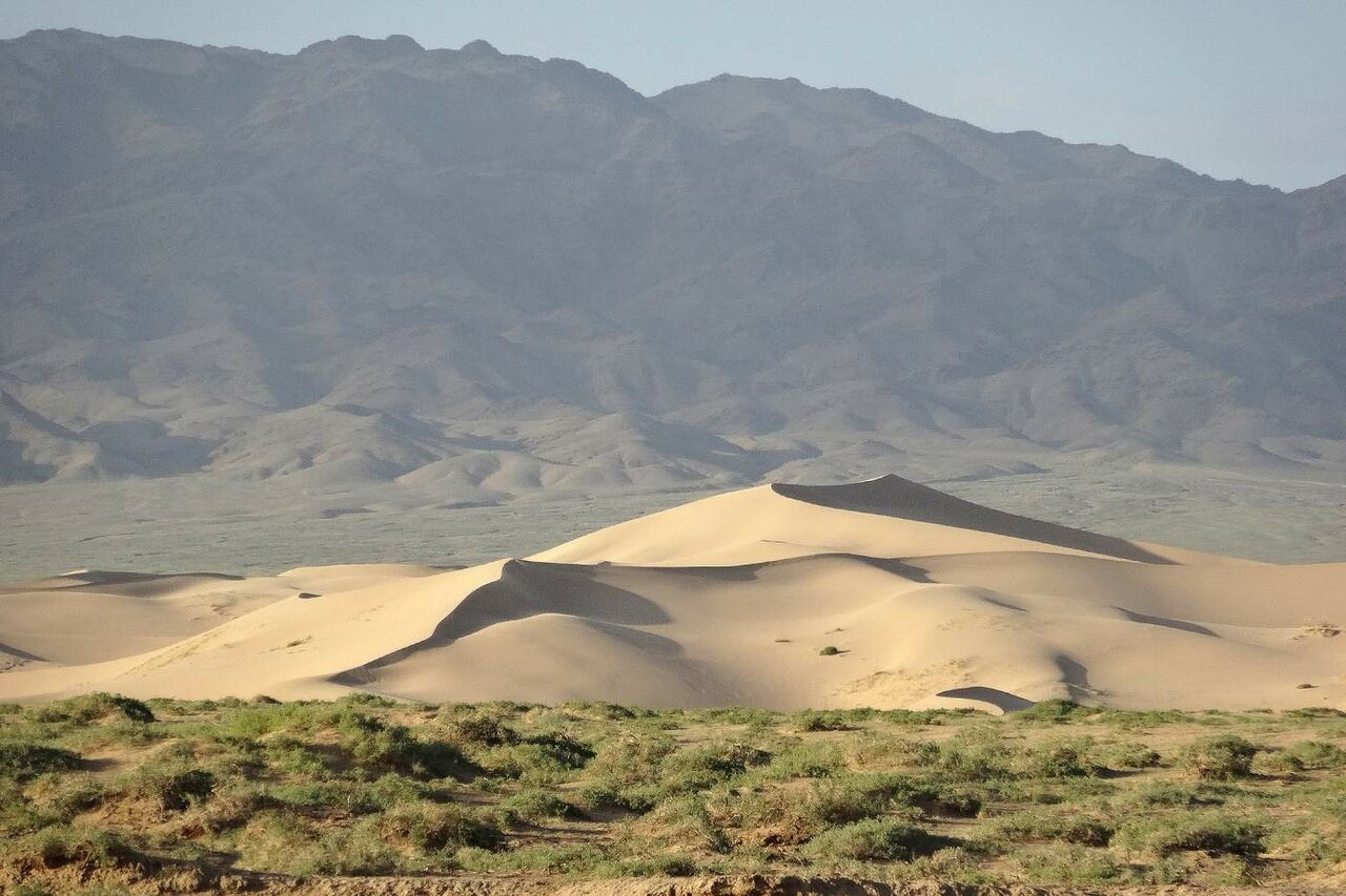 Sanddünen erheben sich unterhalb einer Bergkette in der Wüste Gobi