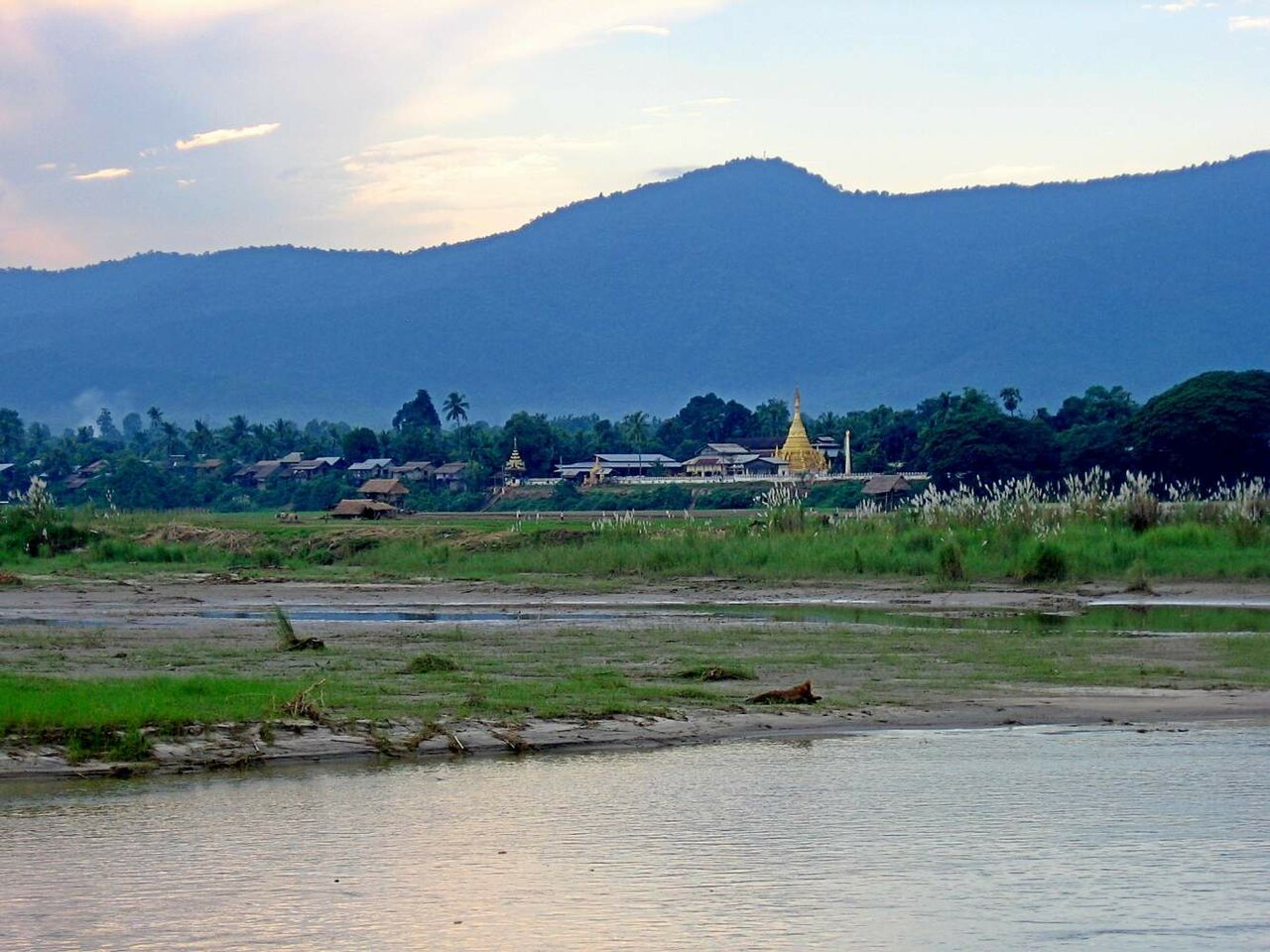 Golden pagoda and riverside village across the Irrawaddy riverbed near Mandalay