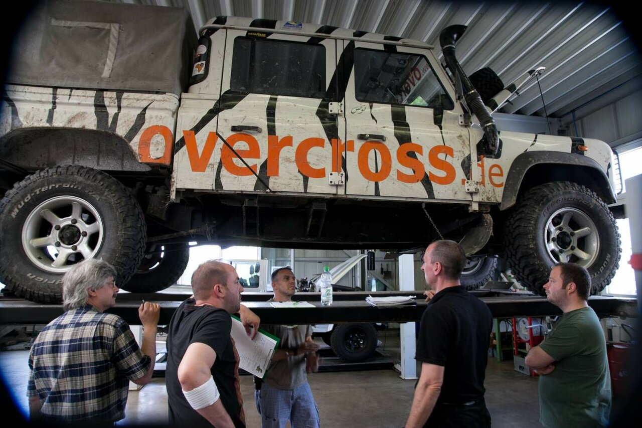 Zebra-gestreifter Land Rover Defender auf der Hebebühne, Teilnehmer betrachten die Unterseite