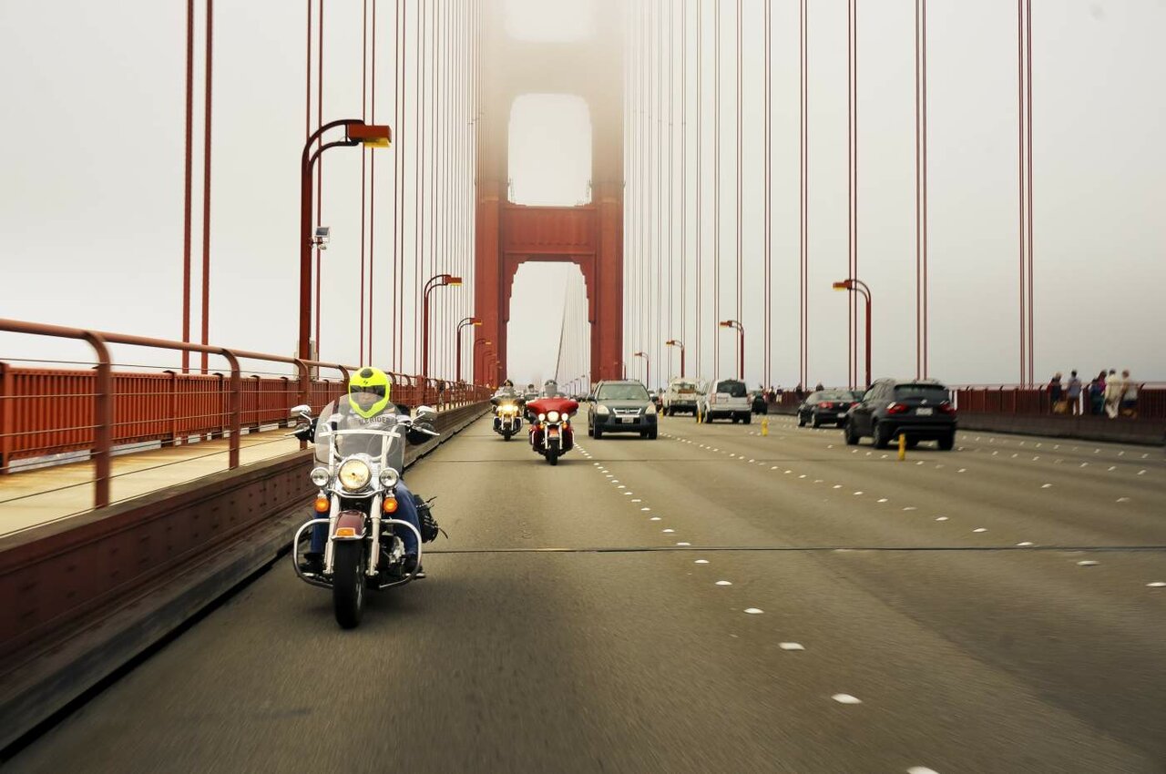 Motorradfahrer überqueren die Golden Gate Bridge im Nebel neben dem Autoverkehr
