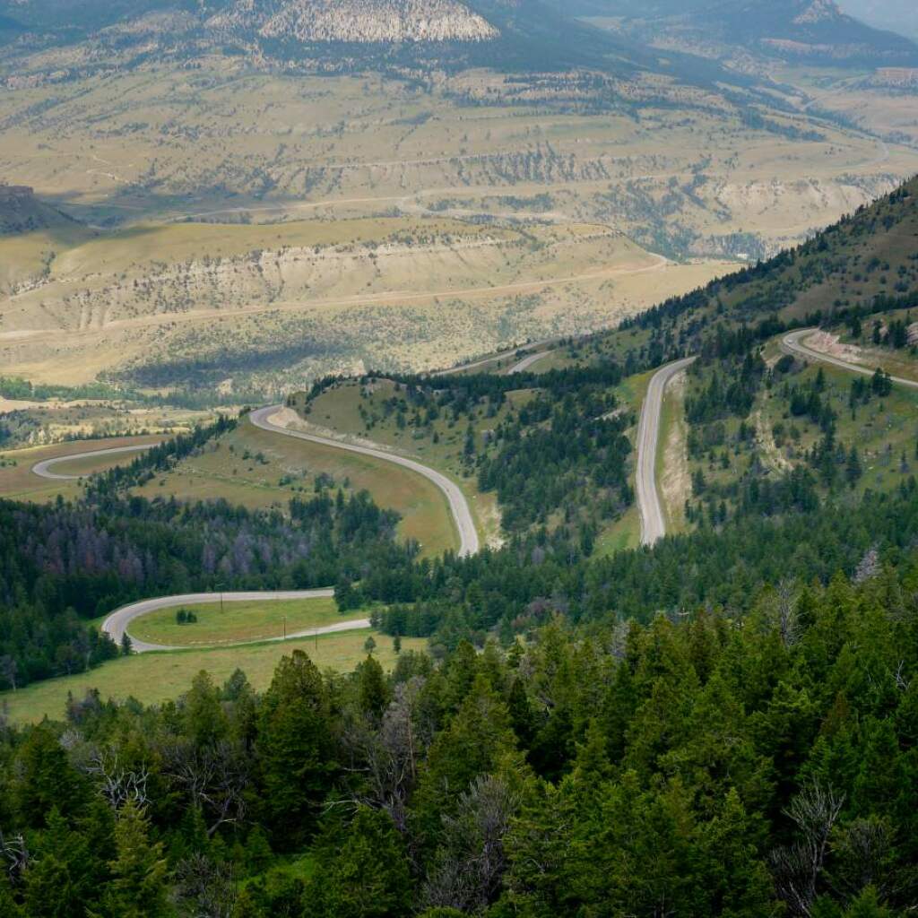 Vista aérea de una carretera de montaña con curvas en zigzag entre laderas boscosas