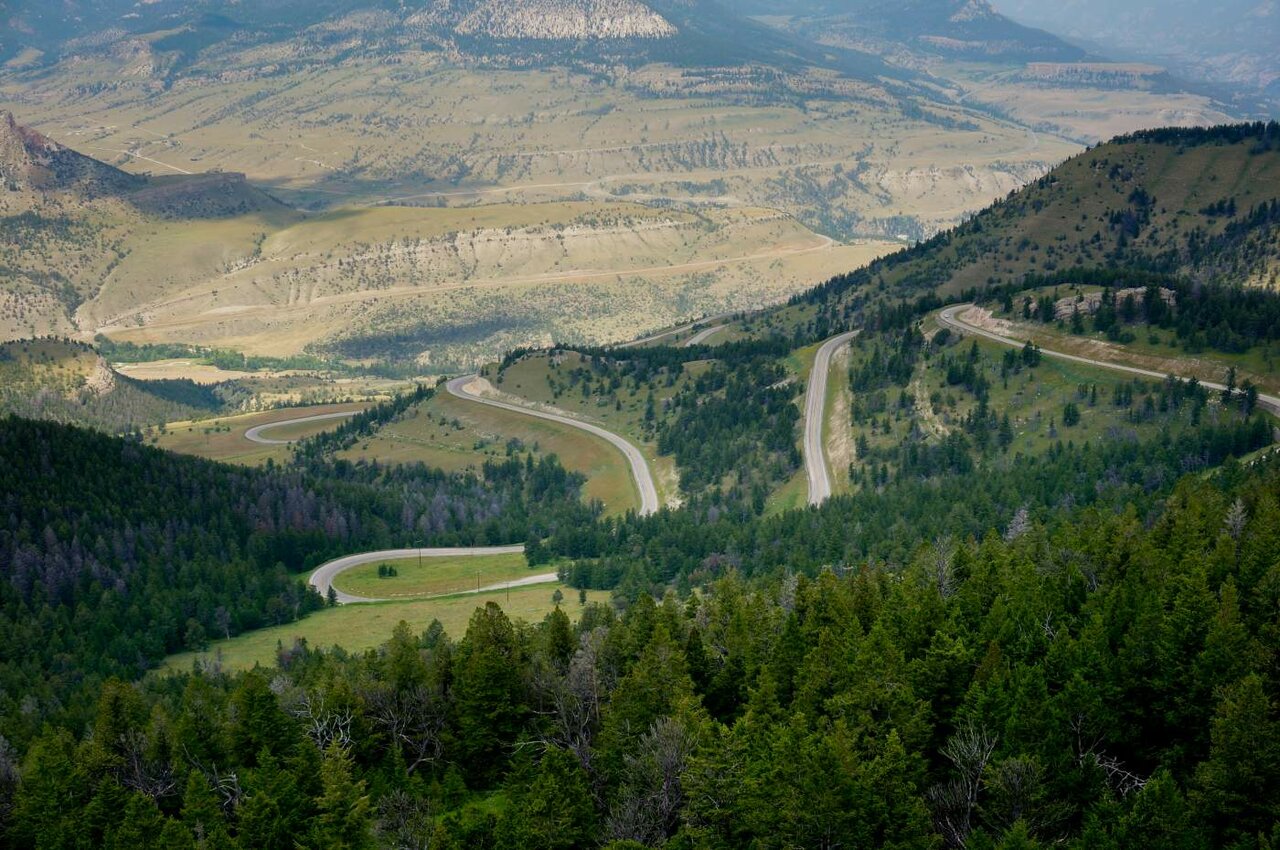 Vista aérea de una carretera de montaña con curvas en zigzag entre laderas boscosas