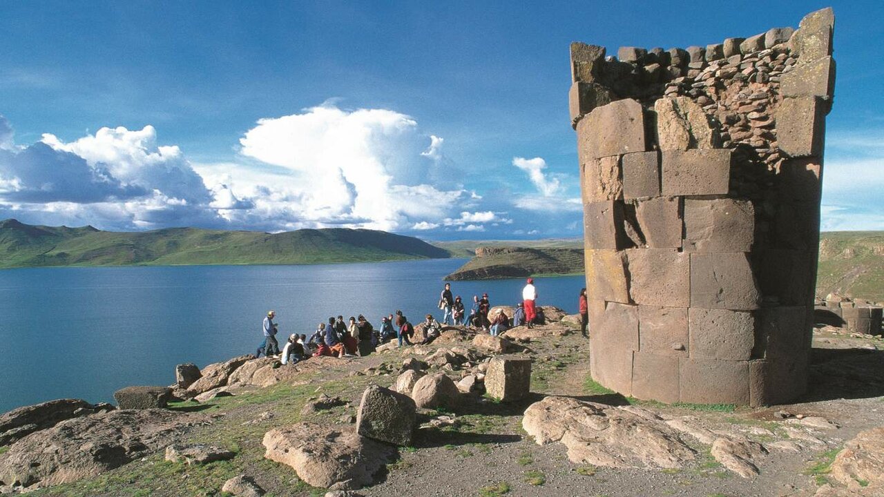 Steinerne Chullpa-Grabtürme in Sillustani mit Blick auf einen See, Touristen in der Nähe