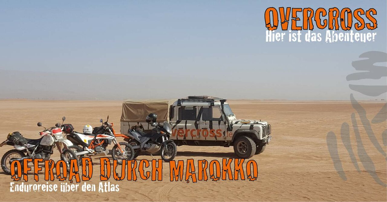 Three motorcycles parked beside an off-road vehicle in the desert