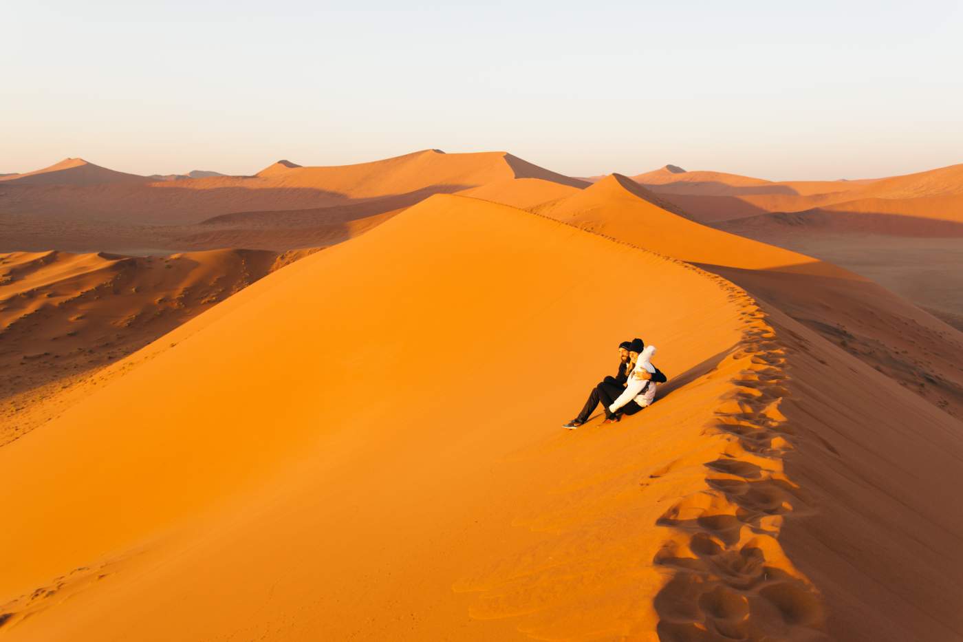 Urlauber der Namibia Explorer Gruppenreise genießen die endlose Weite der namibischen Wüste auf der Dune 45 sitzend.