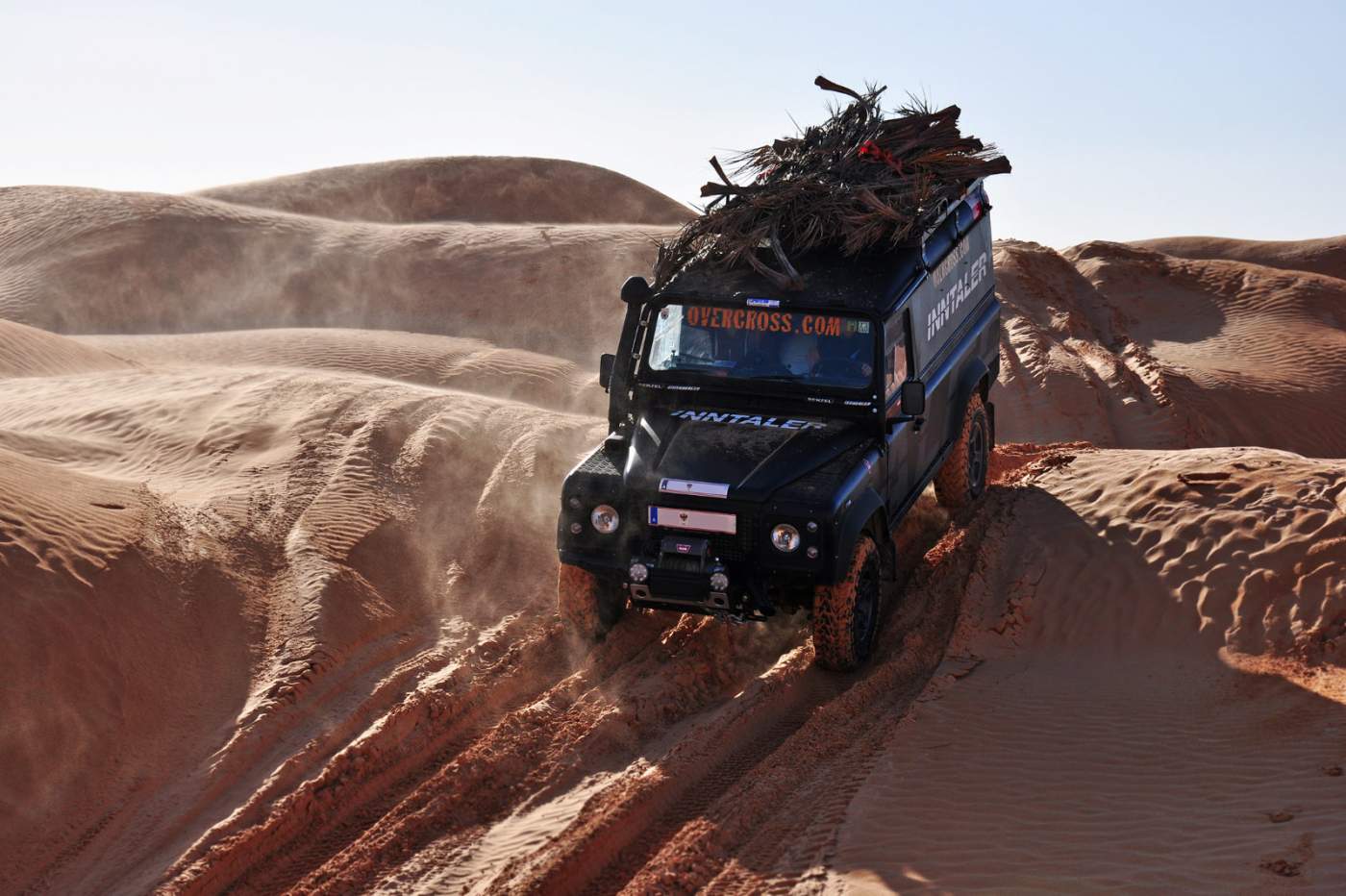 Mit Feuerholz beladener Geländewagen kämpft sich durch Dünenfelder