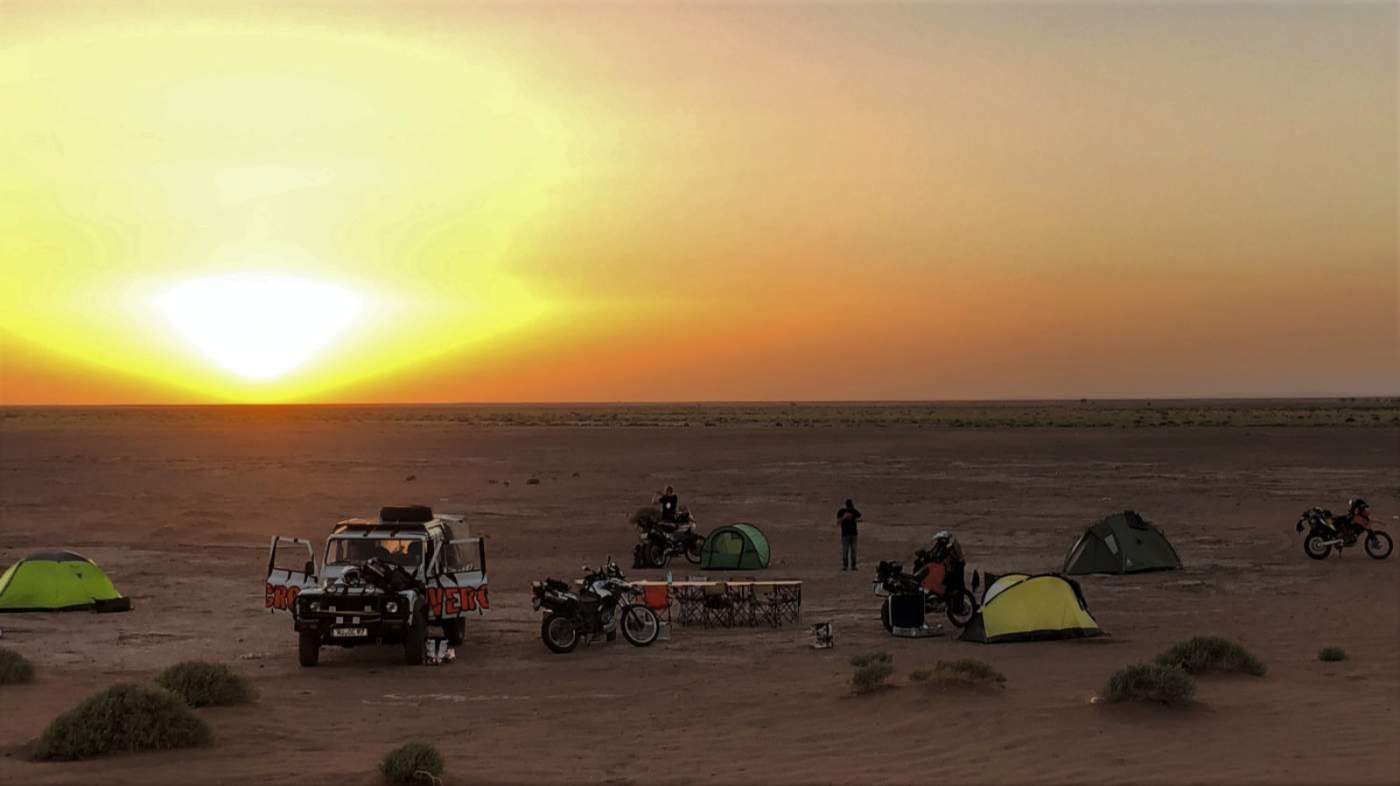 Zelte und Motorräder in einem WIldcamp vor der Oasenstadt Mhamid
