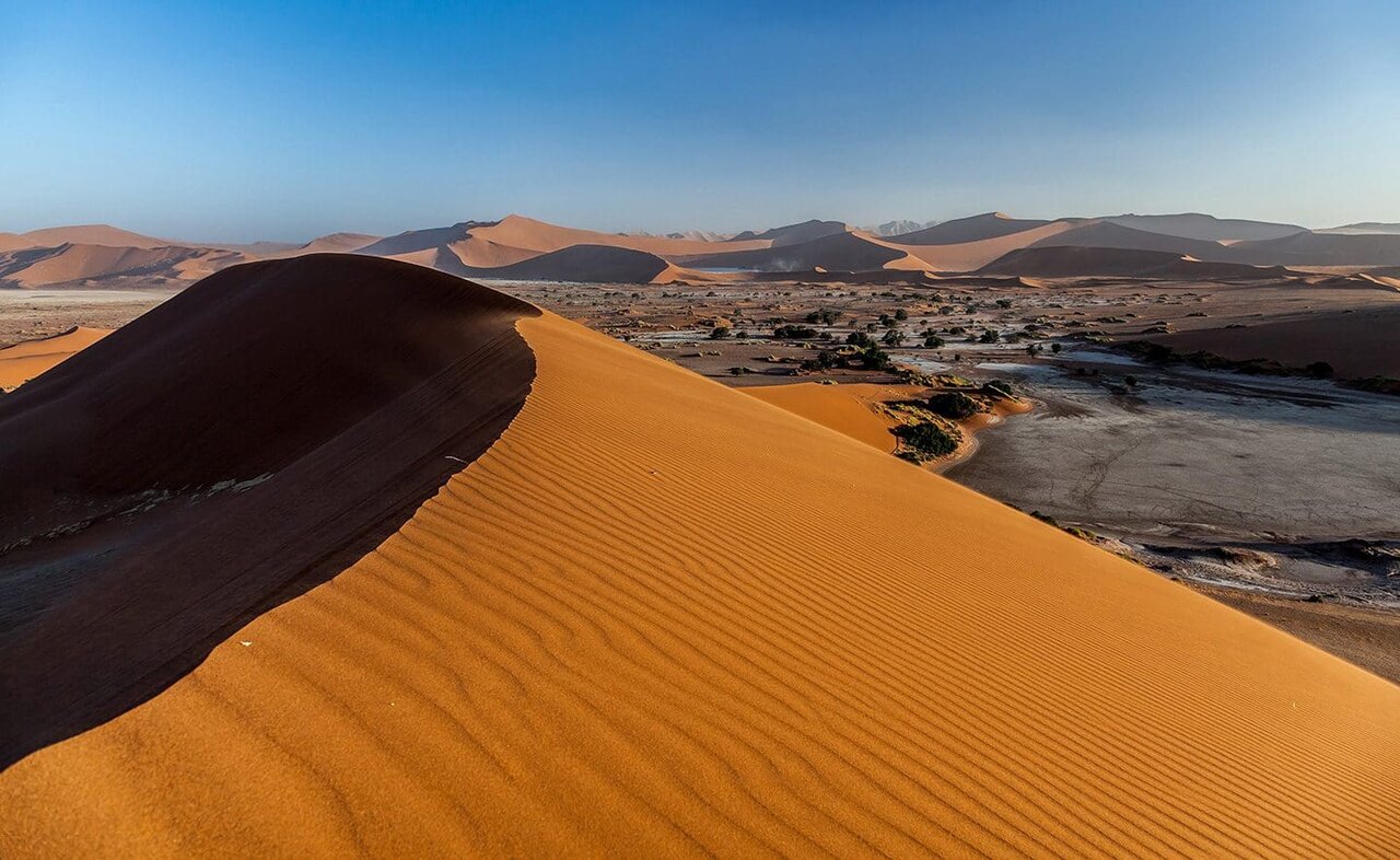 Eine große rote Sanddüne erhebt sich über der Namib-Wüste, in der Ferne kleinere Dünen